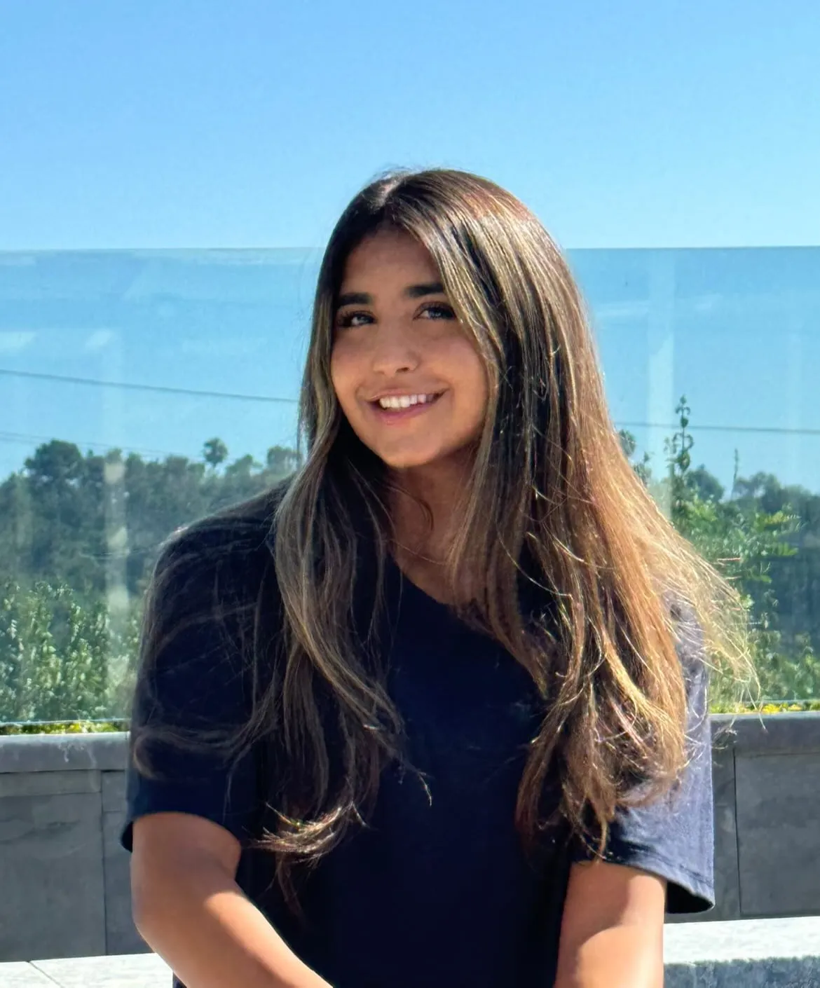 Arisan Hatamabad on a terrace with a glass railing and clear sky, wearing a navy T-shirt